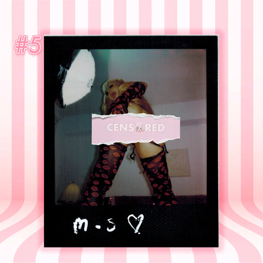 A Polaroid-style photo print centered on a pink striped background. The print shows a person wearing black thigh-high stockings with red lip prints, with a pink censor bar over the torso and white handwritten text at the bottom reading 'm.