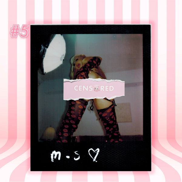 A Polaroid-style photo print centered on a pink striped background. The print shows a person wearing black thigh-high stockings with red lip prints, with a pink censor bar over the torso and white handwritten text at the bottom reading 'm.