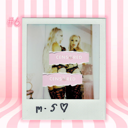 A Polaroid-style photo print centered on a pink striped background. The print shows two women in revealing black outfits with pink censor bars over their faces, and the Polaroid border has handwritten text reading 'm.